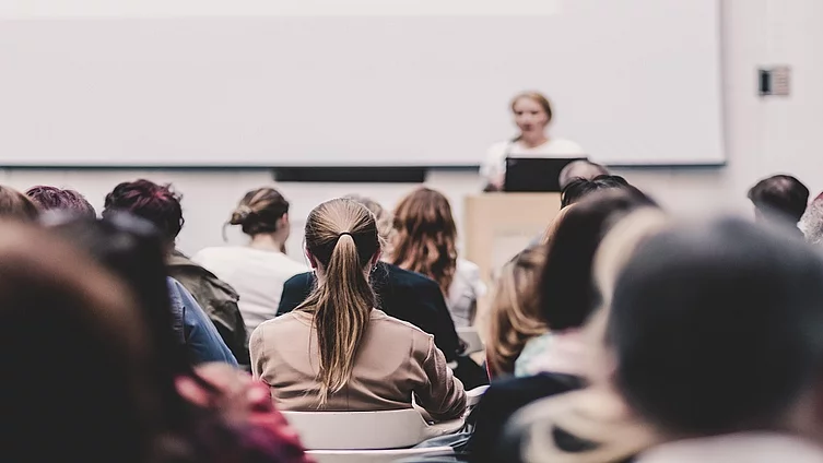 A female speaker speaking in front of an audience in a large conference hall