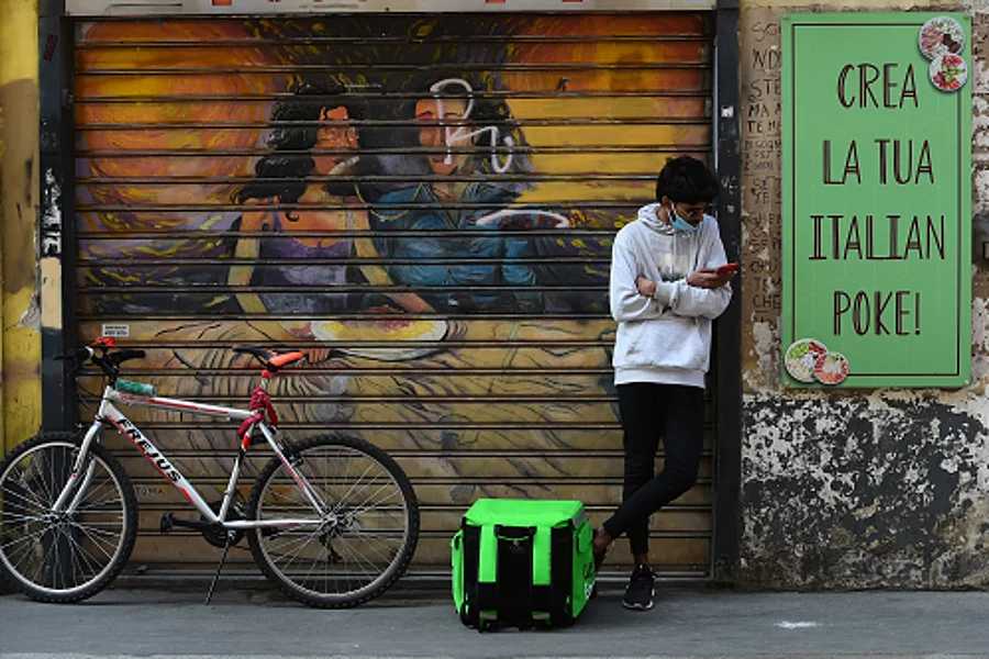 A rider of delivery worker with the Uber Eats Box wait in front of restaurant 