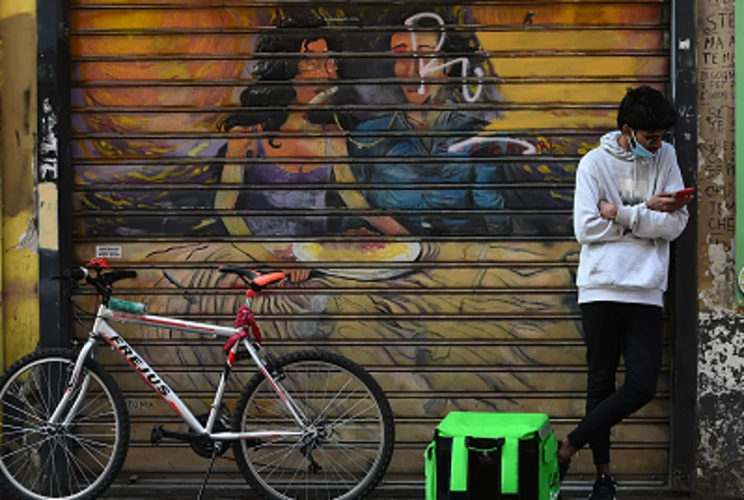 A rider of delivery worker with the Uber Eats Box wait in front of restaurant 