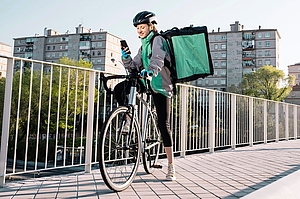A female delivery worker stopping on a bridge to use her phone