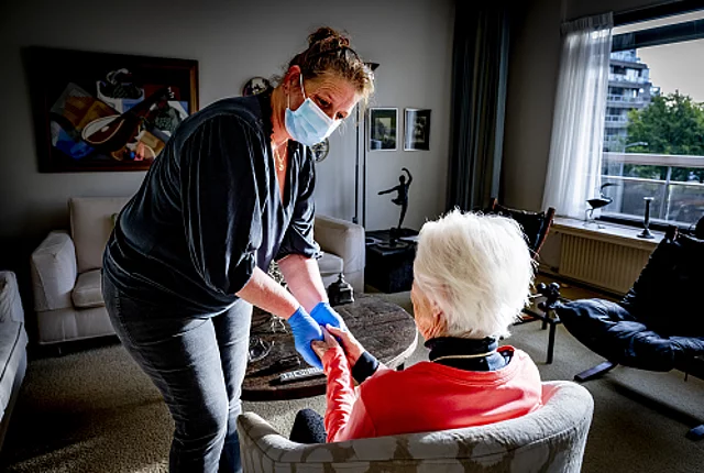 An old woman receives help at home by a home care worker who provides nursing and care at home