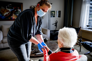 An old woman receives help at home by a home care worker who provides nursing and care at home
