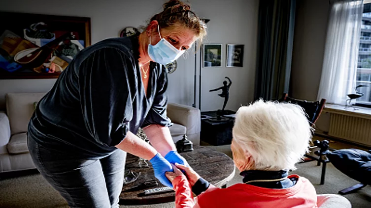 An old woman receives help at home by a home care worker who provides nursing and care at home